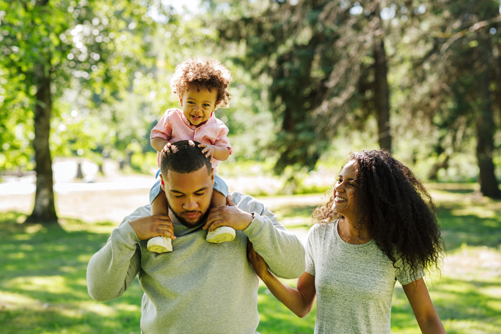 Happy baby girl and his parents walking in the park on a sunny day