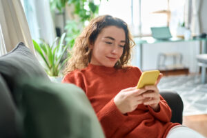 A young woman checks her credit score from the comfort of her sofa using digital banking.